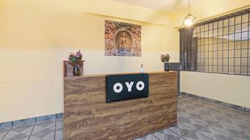 En receptionsdisk med et skilt, der viser 'OYO', i et moderne interiør med mønstret gulv og en dekorativ vægdekoration over disken.