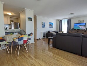 A living room with a sofa, a television, and a dining area with chairs and a table. - Fantastic sunny arty apartment, fully equipped and furnished for short let (Southbank)
