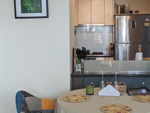 A modern kitchen with stainless steel appliances, a dining table with placemats, and a framed picture on the wall. - Fantastic sunny arty apartment, fully equipped and furnished for short let (Southbank)