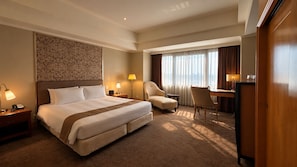 A hotel room with a large bed, two chairs, a desk, and a view of the city through the window. - BERI HOTEL Kaohsiung (Kaohsiung City)