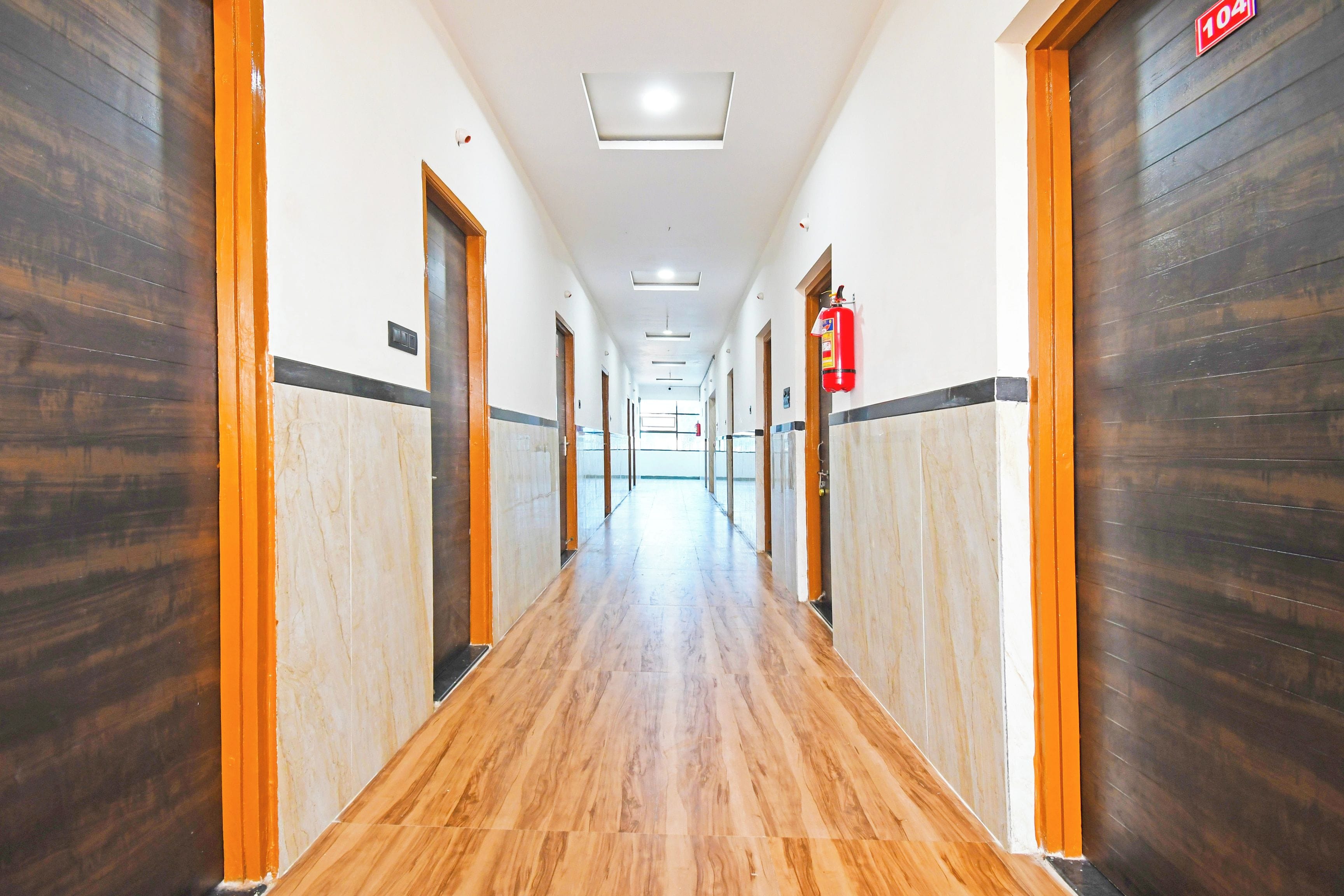 A long, narrow hallway with wooden flooring and doors on both sides.