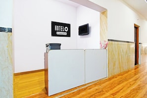 Bancada de recepção com uma placa que diz 'HOTEL Company-Serviced'.