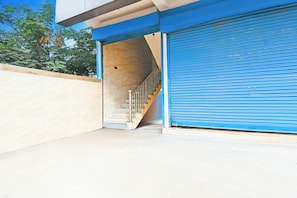 A building entrance with a blue garage door, a staircase leading to an upper level, and a beige wall.