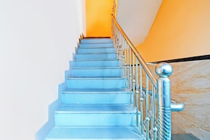 A staircase with a metal railing and a marble wall.