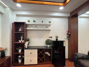 A modern living room with a wooden cabinet, a black sofa, and a small black refrigerator. - Cozy 1-bedroom apartment in beautiful Hyderabad with AC (Hyderabad)