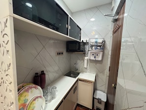 A compact kitchen with a microwave, water dispenser, and a sink. - Cozy 1-bedroom apartment in beautiful Hyderabad with AC (Hyderabad)
