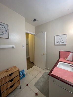 A bathroom with a sink, mirror, and towel rack. There is a door leading to another room. - Cozy 1-bedroom apartment in peaceful Fresno with AC (Fresno)
