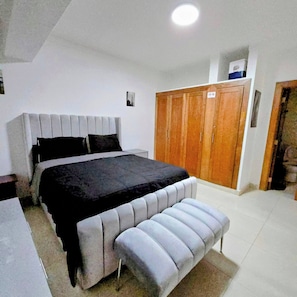Une chambre à coucher avec un lit, un banc, une armoire et un luminaire au plafond.