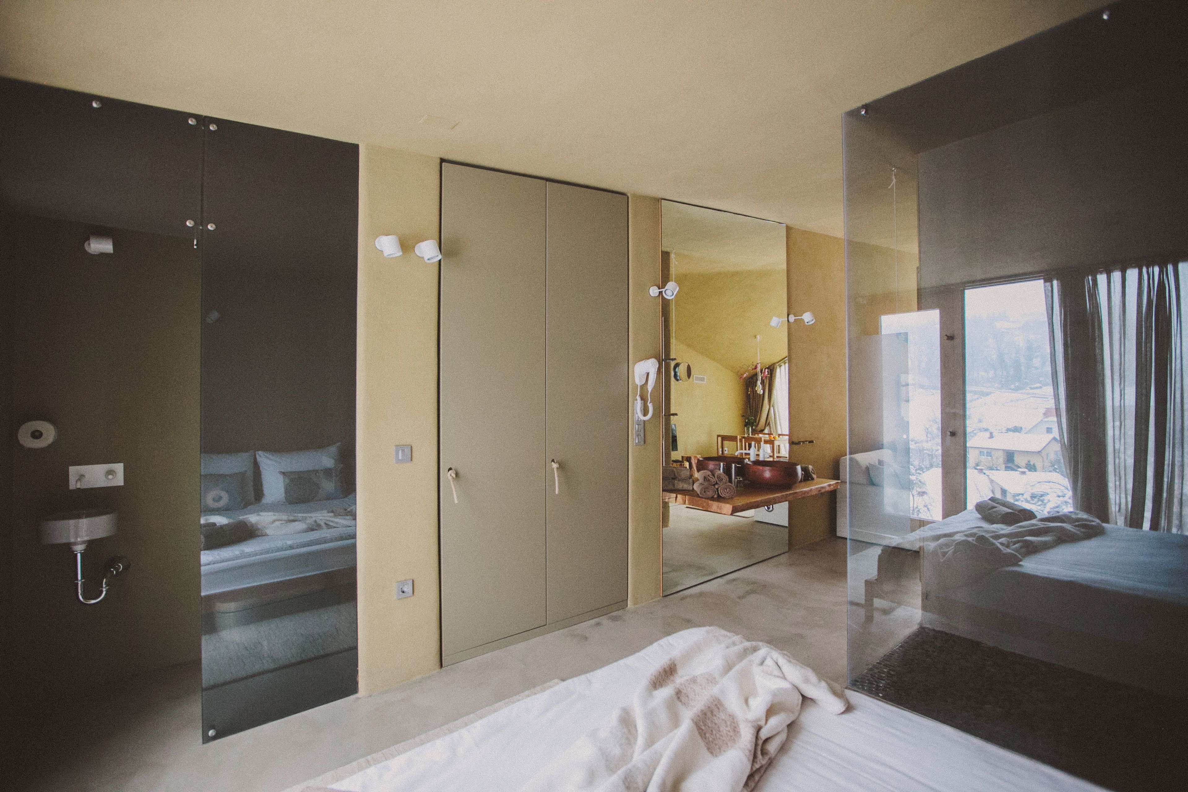 Una camera d'albergo moderna con un letto grande, uno specchio, un armadio e un bagno.