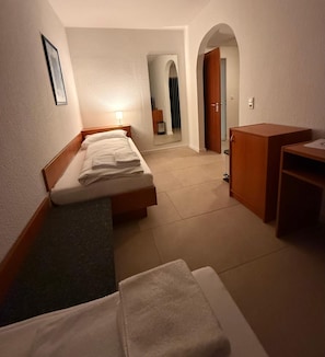 A hotel room with two beds, a desk, a wardrobe, and a mirror. - Hotel G&k (Giesen)