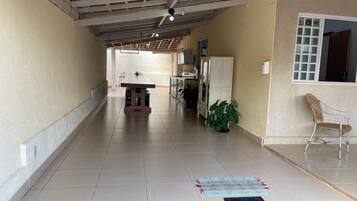 Um corredor com piso de azulejos, uma mesa de jantar, um vaso de planta, uma cadeira e uma janela com vista.