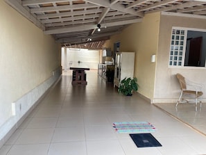 A corridor with a tiled floor, a dining table, a potted plant, a chair, and a window with a view. - Pousada Xero (Capitólio)