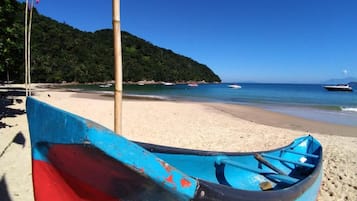 Uma praia com um barco a remo e um mastro.