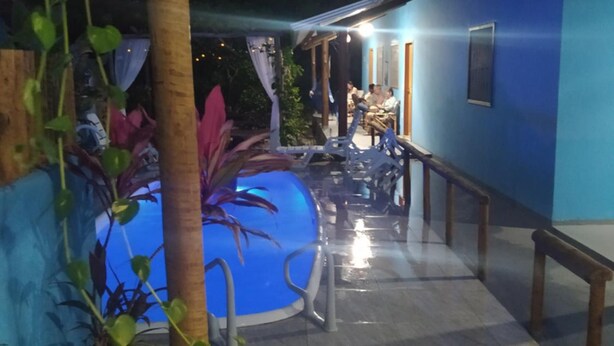 Un espace extérieur doté d’une piscine, de coins salon et d’un bâtiment à la façade bleue.