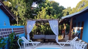 Une piscine entourée de chaises longues blanches et dotée d’un espace salon abrité.