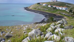 Un paysage côtier avec un phare, une côte rocheuse et des bâtiments blancs aux toits rouges.