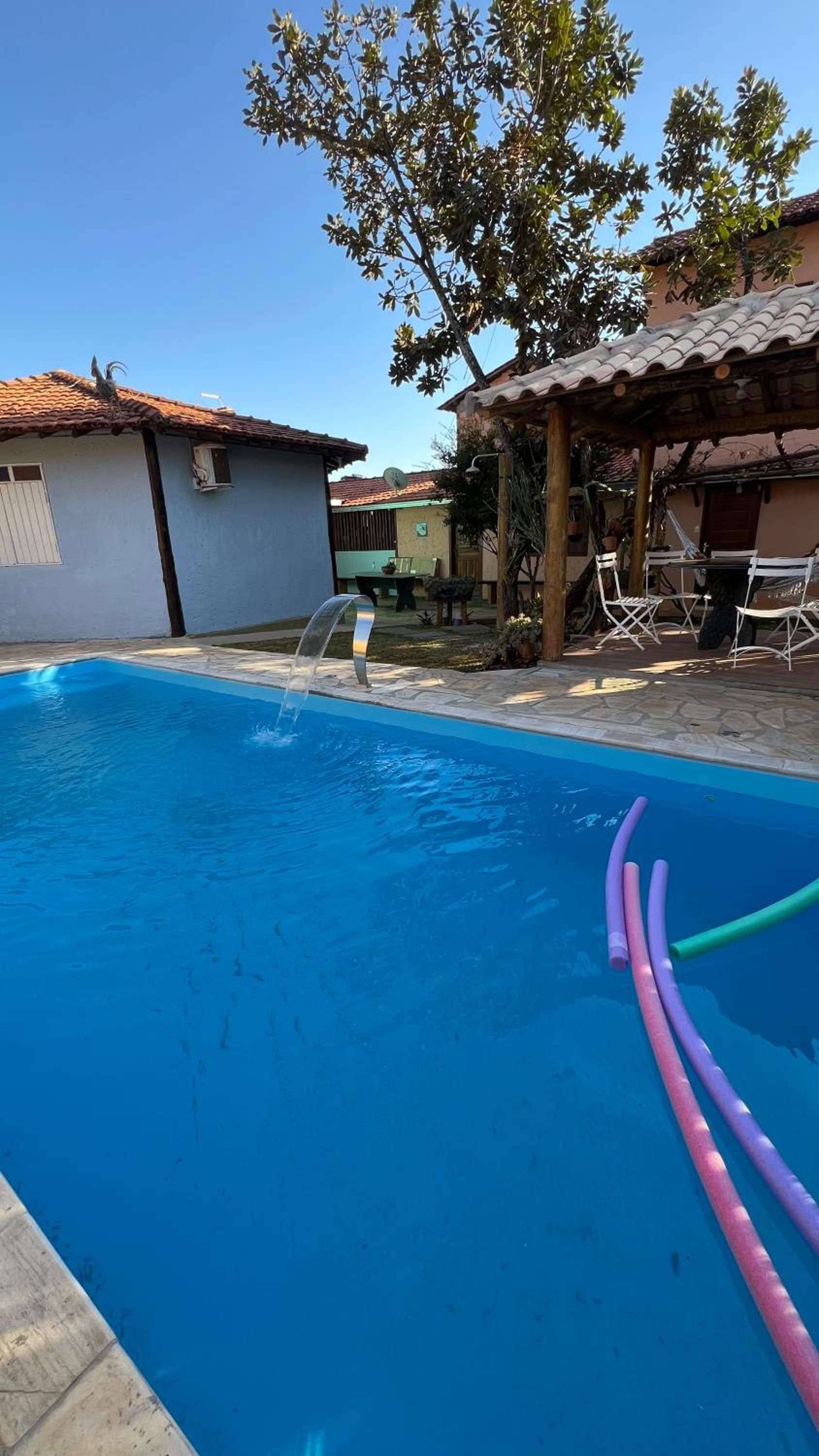 Piscina com um elemento aquático, rodeada por um pátio com mobiliário de exterior.