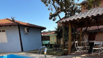 Piscina com um elemento aquático, rodeada por um pátio com mobiliário de exterior.