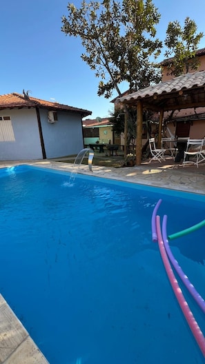 En pool med en vattenfontän, omgiven av en uteplats med utemöbler.