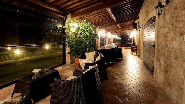 An outdoor patio area with wicker furniture, a large potted plant, and a view of the night sky. - Villa Klinai (Cerveteri)