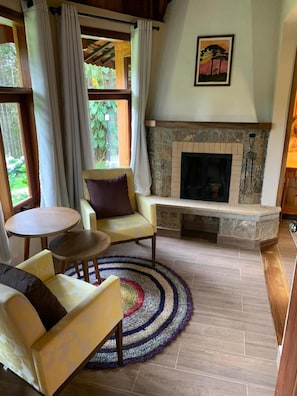 Una sala de estar acogedora con chimenea, un sofá, una mesa redonda de centro y una alfombra colorida.