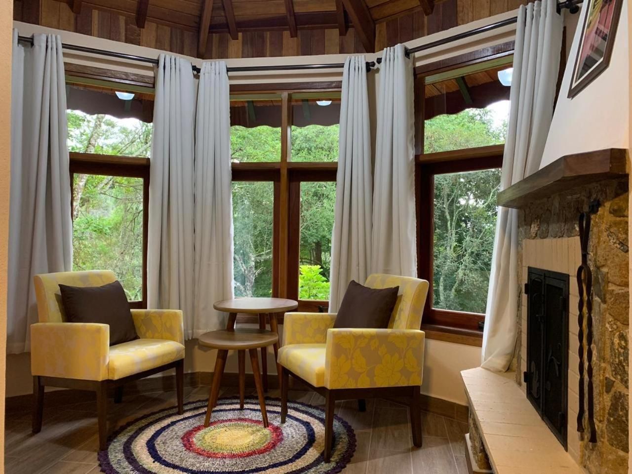 Una habitación con dos sillones amarillos, una mesita redonda y una chimenea.