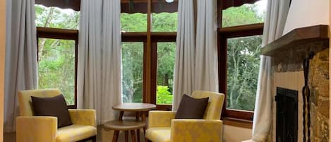Una habitación con dos sillones amarillos, una mesita redonda y una chimenea.