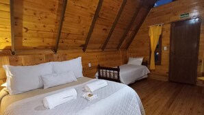 A wooden cabin with two beds, each with white bedding and pillows, a wooden ceiling, and a door labeled 'SAIDA'. - Estalagem Refúgio Do Capão (Cambara do Sul)