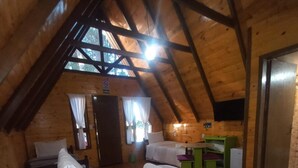 A cozy attic bedroom with a sloped ceiling, a bed with pillows, a small table, and a television mounted on the wall. - Estalagem Refúgio Do Capão (Cambara do Sul)
