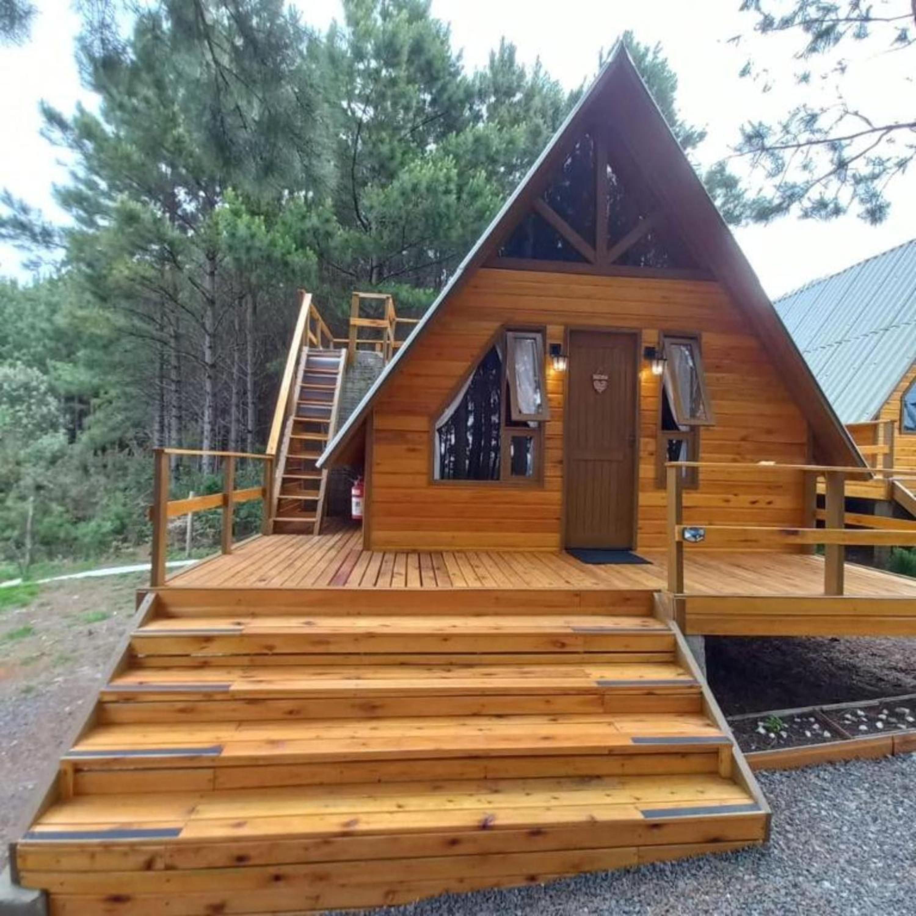 Uma cabana de madeira com telhado inclinado e um deck, com escadas que levam à entrada.