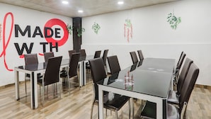 Ein Konferenzraum mit einem Glastisch, Ledersesseln und einer Wand mit dem Schriftzug 'MADE WITH'.