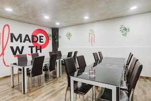 A conference room with a glass table, leather chairs, and a wall with a 'MADE WITH' sign. - OYO Townhouse Awas Vikas Kalyanpur (Kanpur)