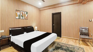 Ein Hotelzimmer mit Bett, Schreibtisch, Stuhl, Deckenventilator und Tür.