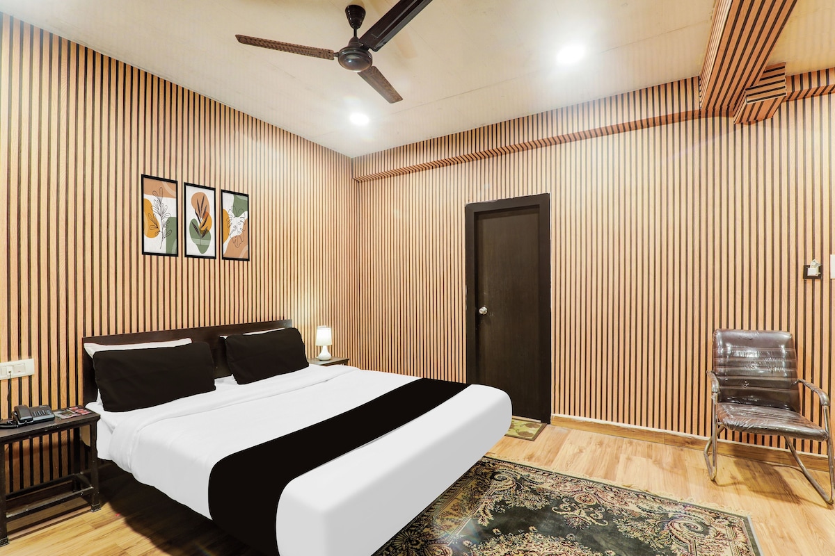Ein Hotelzimmer mit Bett, Schreibtisch, Stuhl, Deckenventilator und Tür.