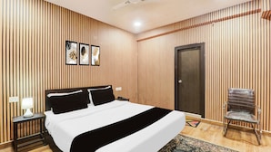 Ein Hotelzimmer mit einem Bett, einem Sessel, einer Tür und einem Deckenventilator.