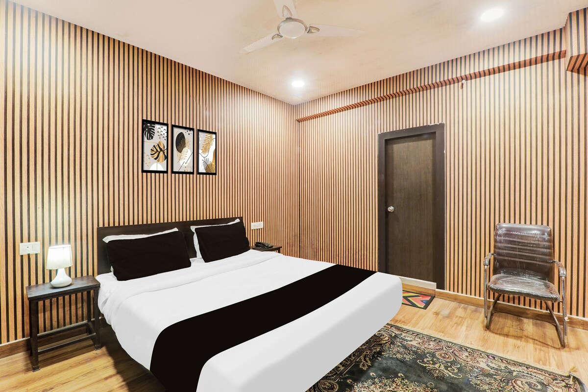 Quarto de hotel com cama, cadeira, porta e ventilador de teto.