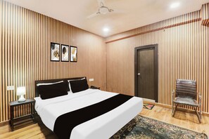 A hotel room with a bed, a chair, a door, and a ceiling fan. - OYO Townhouse Awas Vikas Kalyanpur (Kanpur)