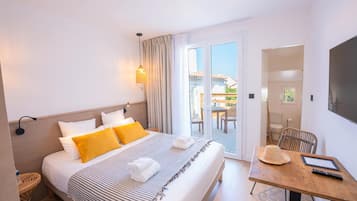 Een hotelkamer met een bed, een tafel, een stoel, een televisie en een balkon met uitzicht.