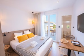 Une chambre d’hôtel avec un lit, une table, une chaise, une télévision et un balcon avec vue.