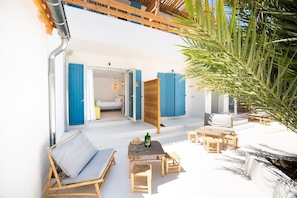 Un espace extérieur ensoleillé, aménagé avec une table en bois, des chaises et un canapé.