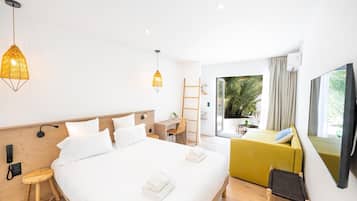 Een moderne hotelkamer met een groot bed, een bureau, een stoel en een bank. Er is een raam met uitzicht op groen.