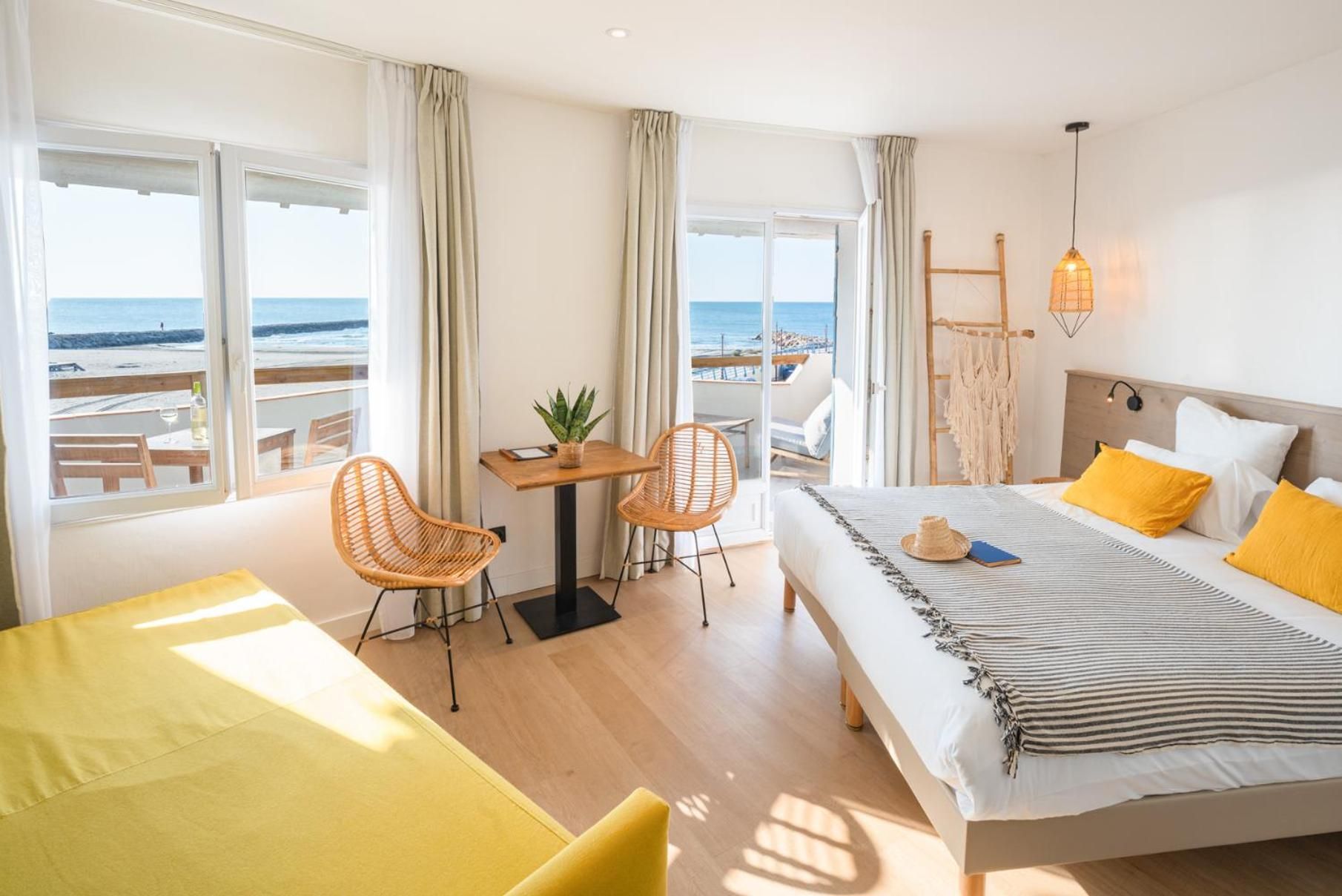 Een hotelkamer met een bed, een bureau, stoelen en uitzicht op het strand.