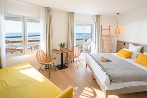 Una habitación de hotel con cama, escritorio, sillas y vista a la playa.