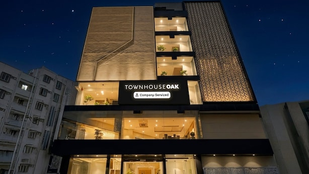 A multi-story building with a sign reading 'TOWNHOUSE OAK' and 'Company-Serviced.' - Townhouse Oak AECS Layout Brookfield (Bangalore)