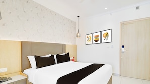 A hotel room with a bed, bedside table, and a wall-mounted artwork. - Townhouse Oak AECS Layout Brookfield (Bangalore)