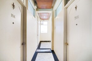 Un pasillo con puertas que llevan la etiqueta '201' y conducen a una habitación con ventana.