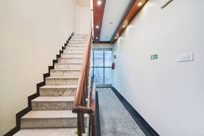 Una escalera de mármol con barandillas de madera que conduce a una puerta con letrero de salida.