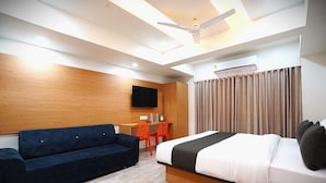 A modern hotel room with a bed, a sofa, a desk, and a television. - hotel orange tree (Ahmedabad)