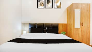 Quarto de hotel com cama, guarda-roupa de madeira e três obras de arte emolduradas na parede.