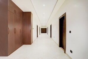 A long, narrow hallway with a polished floor, wooden doors, and a plain wall. - Super Townhouse Oak AIIMS Walmi (Danapur)